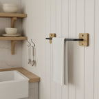 Oak and black metal towel rack with a white towel mounted on a wall in a kitchen setting.
