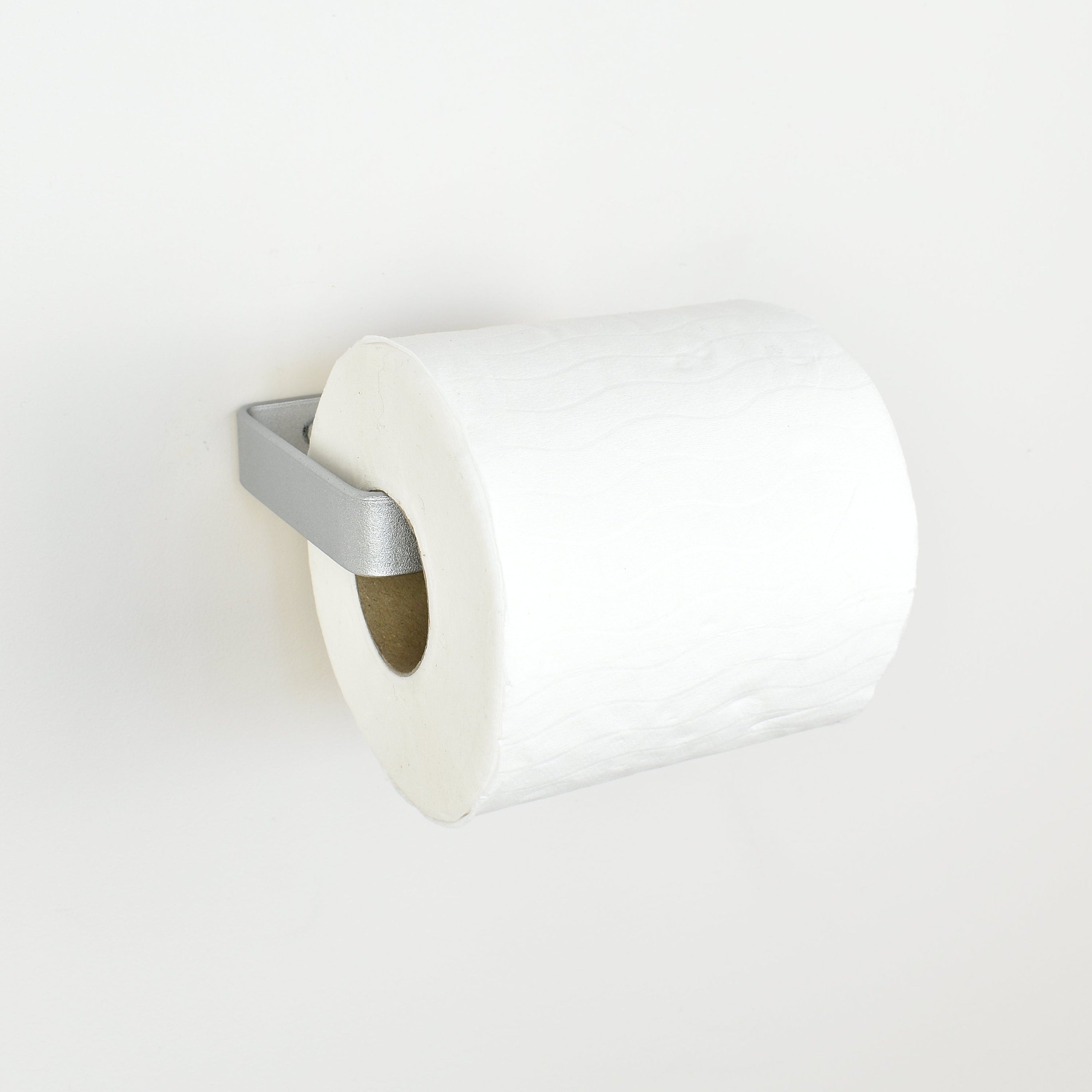 Metallic silver metal toilet paper holder left view showing toilet roll in place