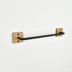 Black towel bar mounted on a white wall with oak fixings.