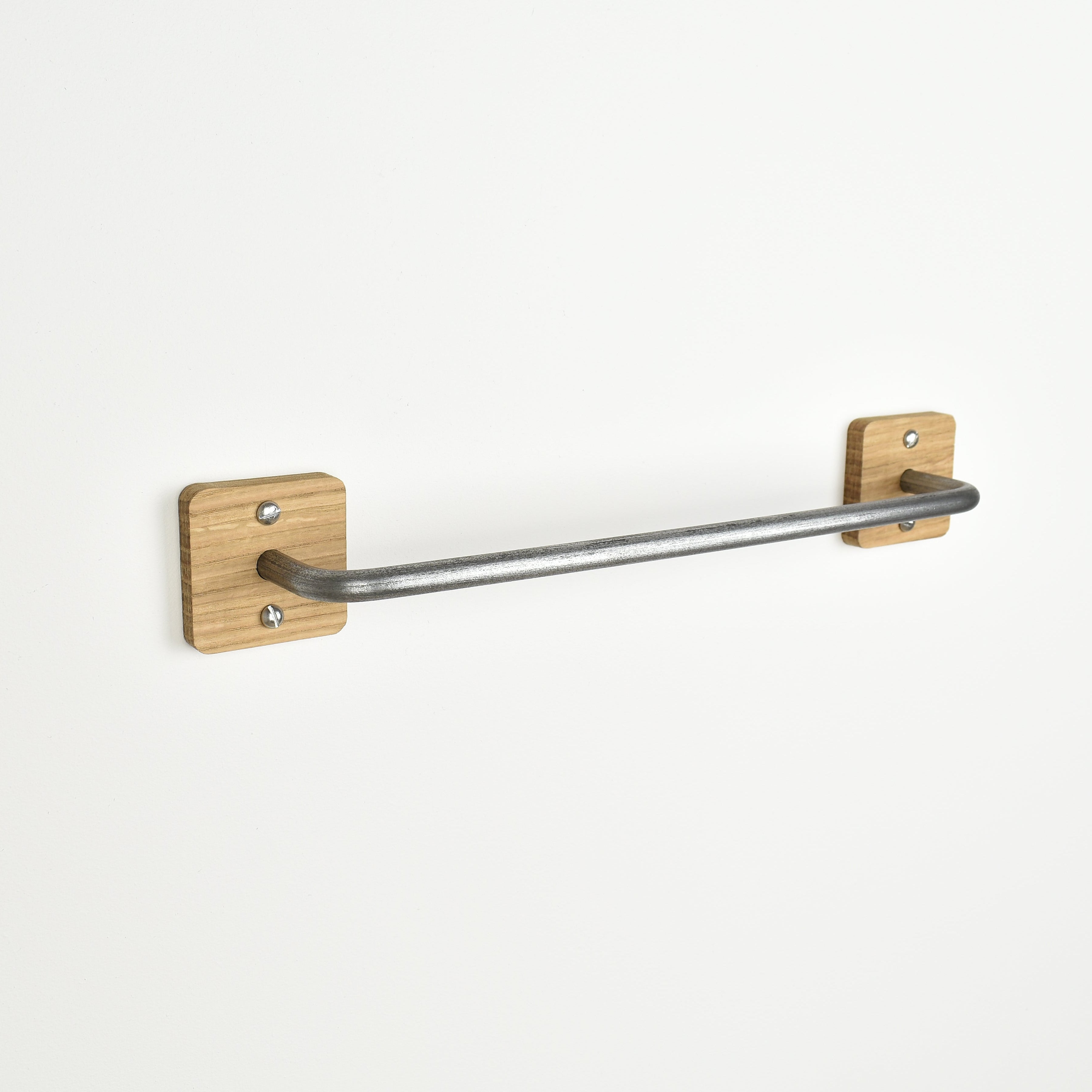 metal towel rack with oak brackets on a white wall