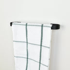 Plaid towel hanging on a black towel rack against a white background - right view