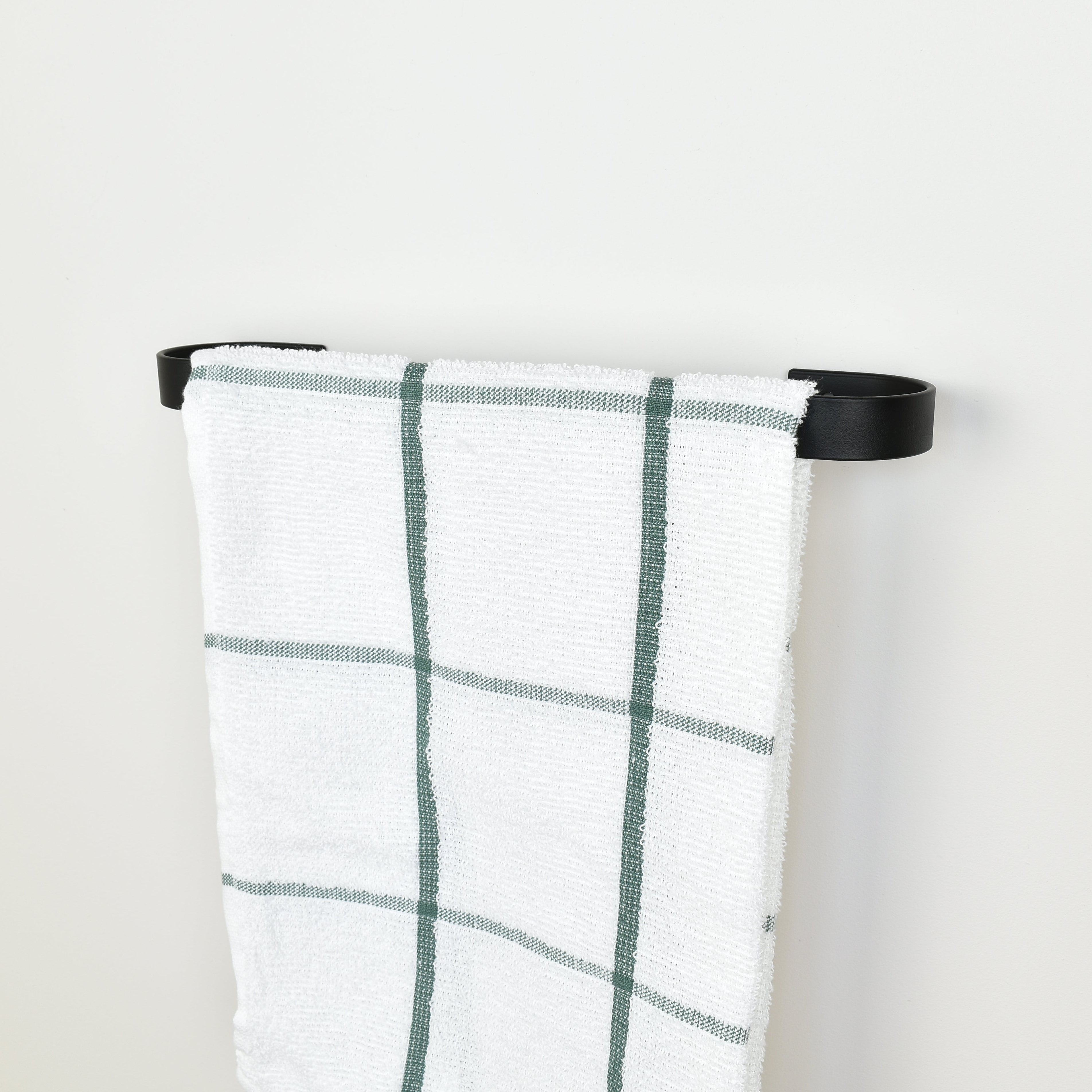 Plaid towel hanging on a black towel rack against a white background - right view