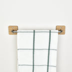 Plaid towel hanging on a oak and pewter steel towel rack against a white background