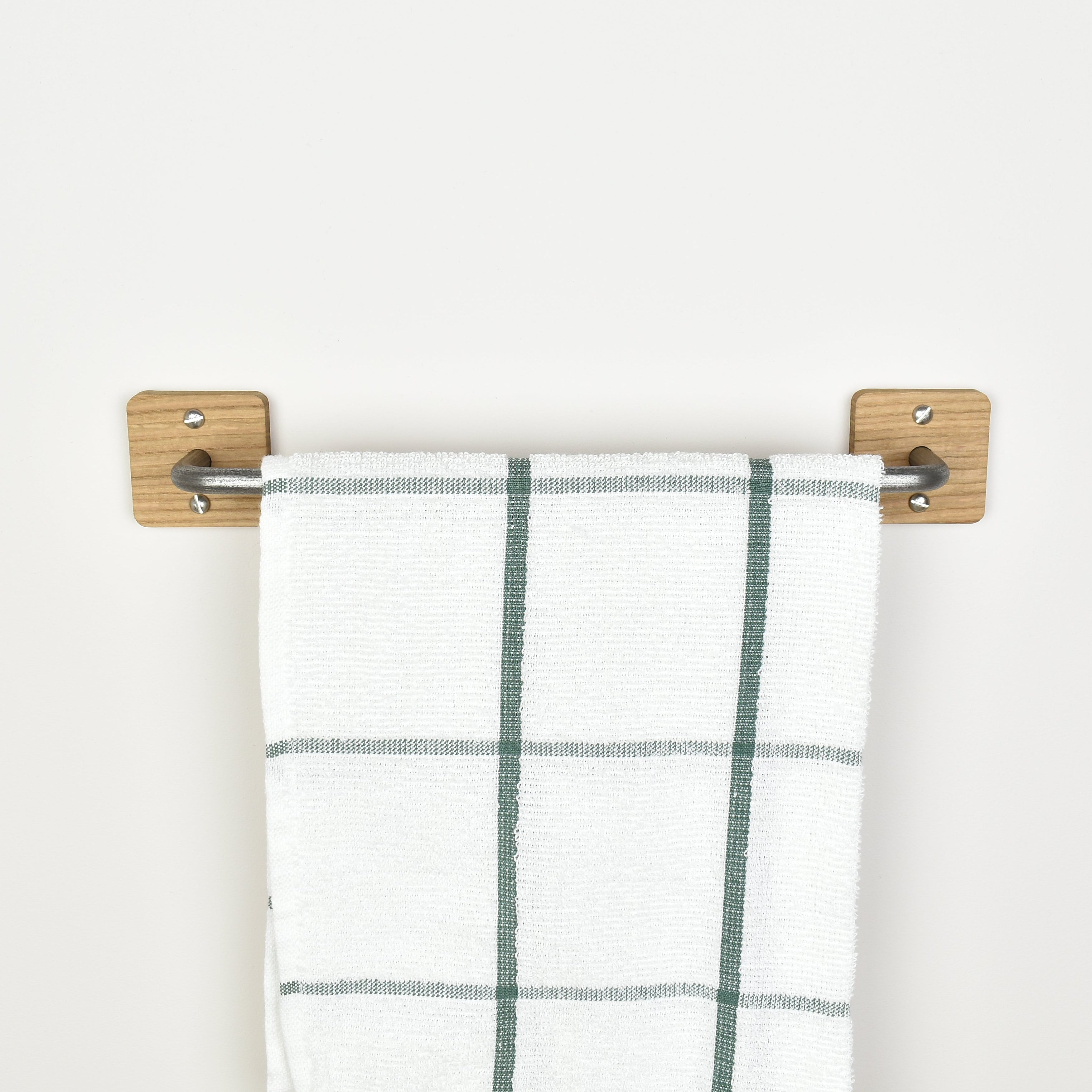 Plaid towel hanging on a oak and pewter steel towel rack against a white background