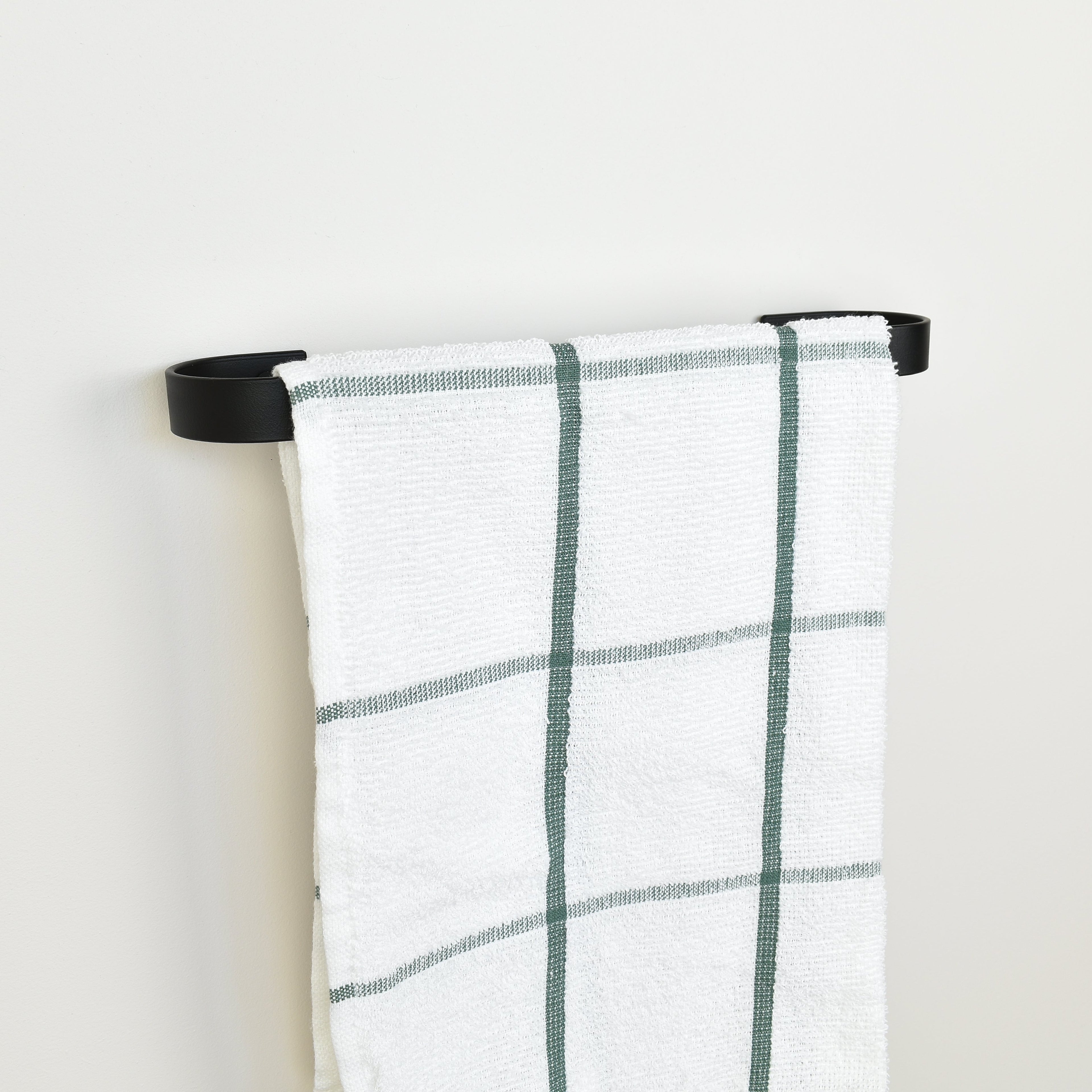 Plaid towel hanging on a black towel rack against a white background - left view