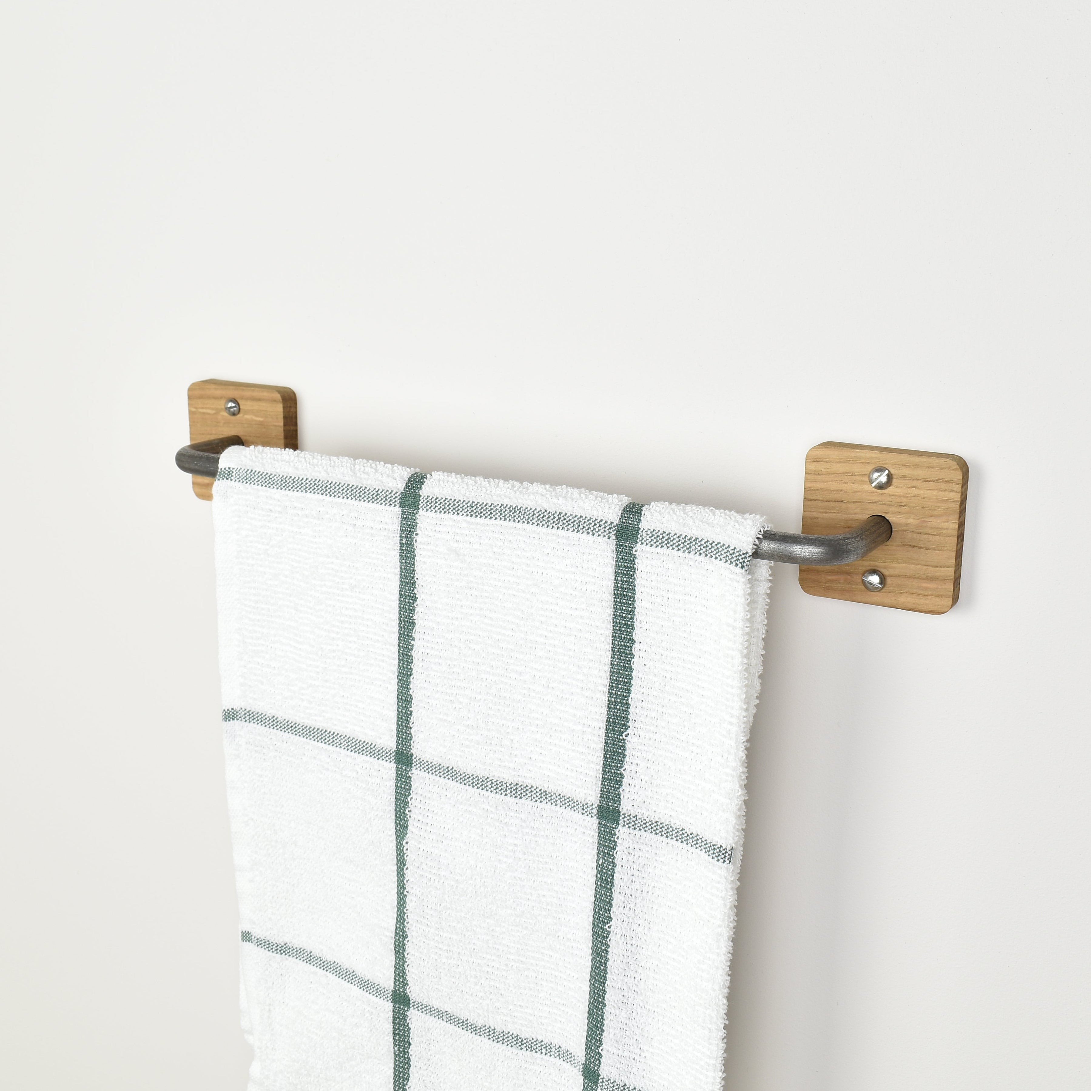 oak and pewter metal towel rack with a plaid towel on a white wall
