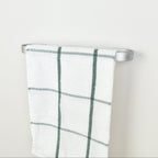 Plaid towel hanging on a silver towel rack against a white background - right view