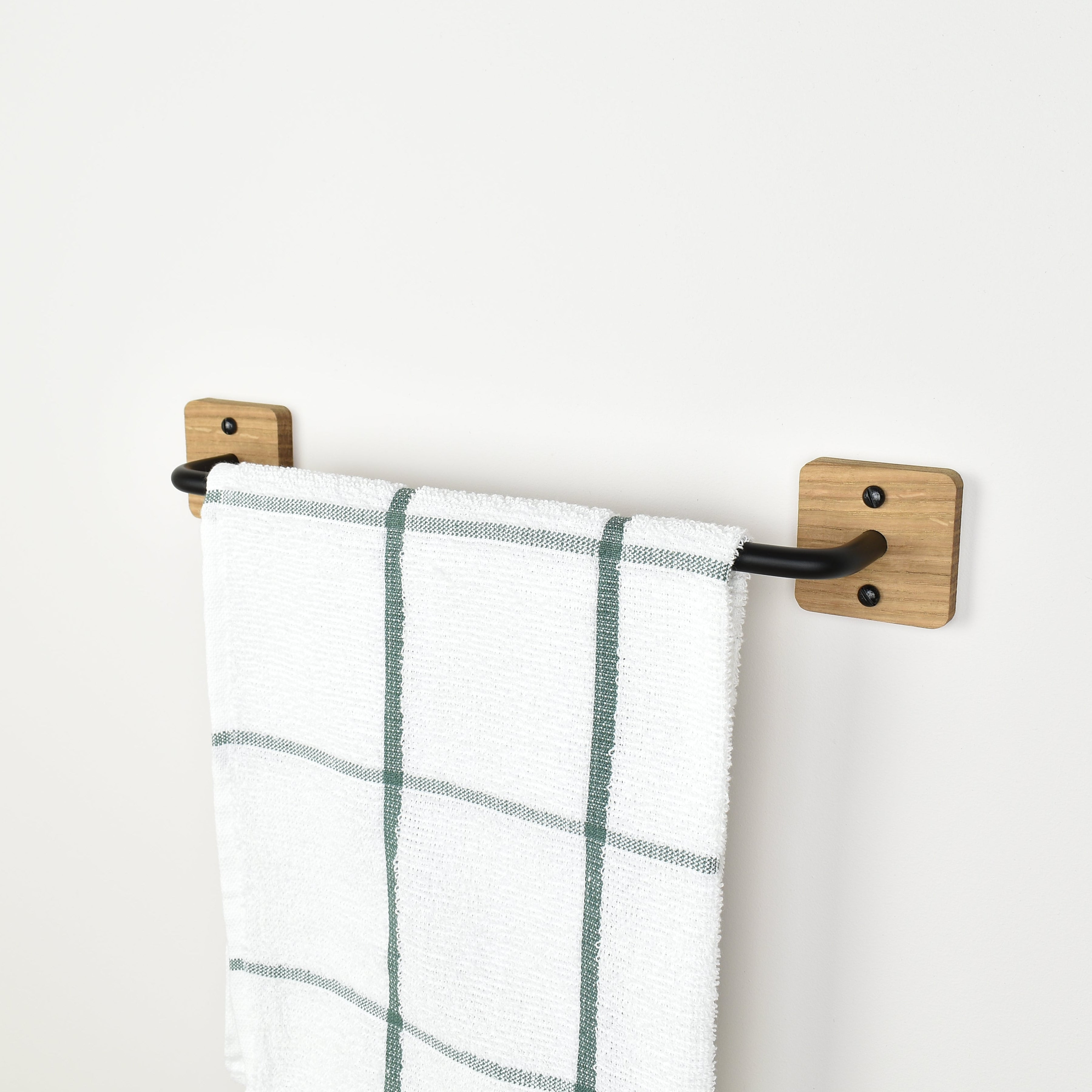 oak and black metal towel rack with a plaid towel on a white wall