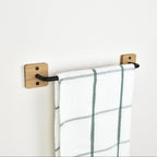 oak and black steel towel rack with a towel on a white wall setting