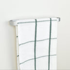 Plaid towel hanging on a silver towel rack against a white background - left view