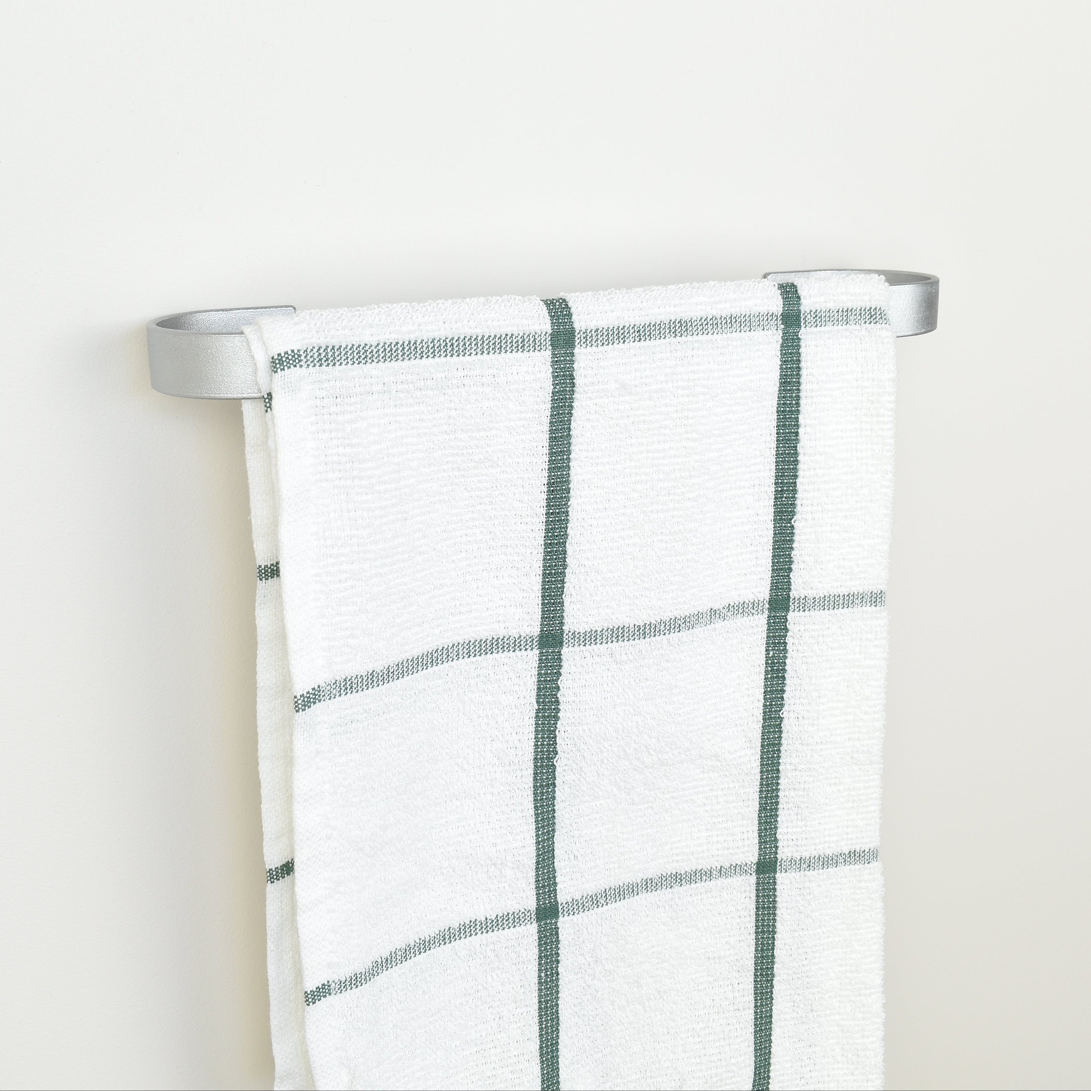 Plaid towel hanging on a silver towel rack against a white background - left view