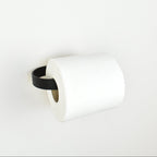roll of toilet paper on a black metal toilet roll holder - left view