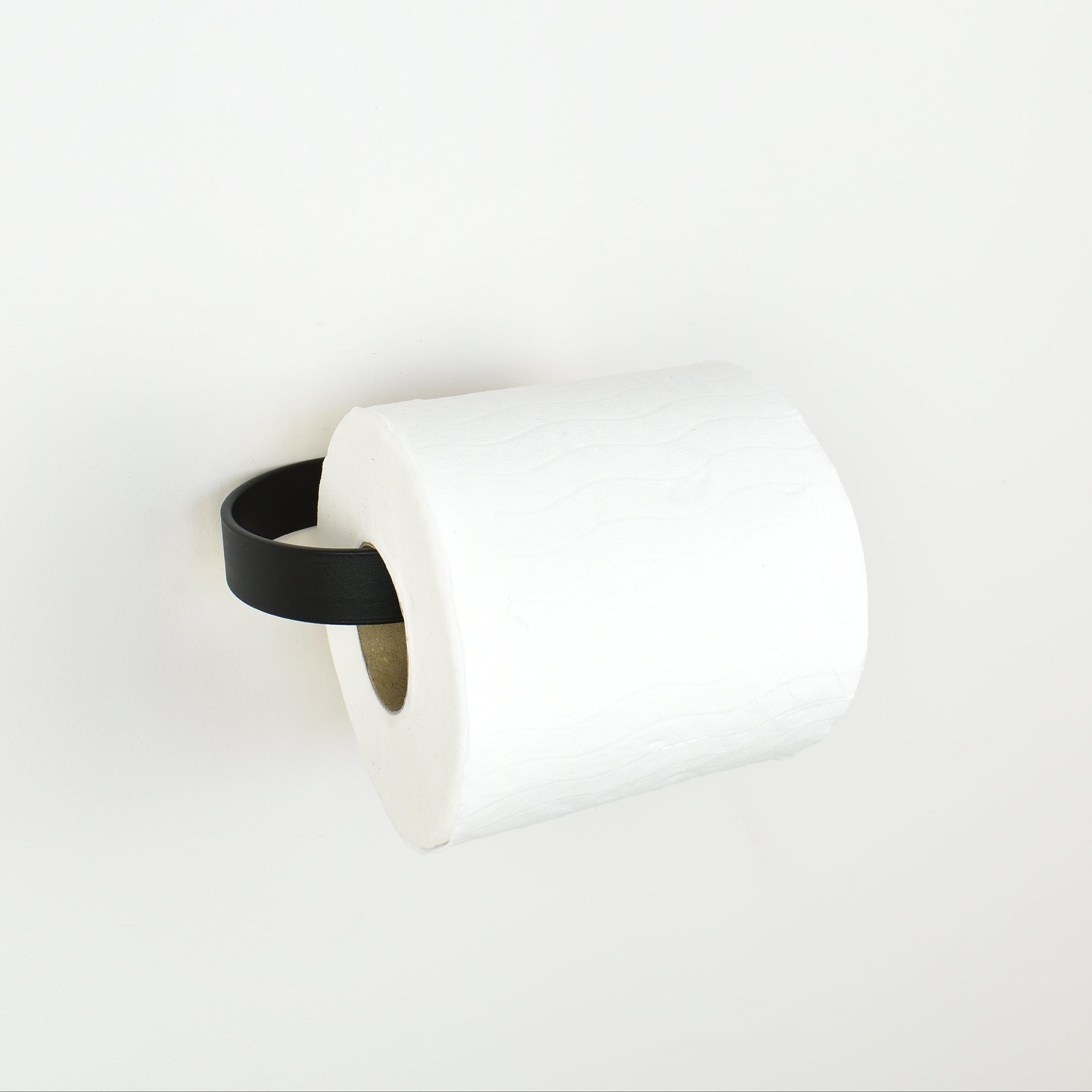 roll of toilet paper on a black metal toilet roll holder - left view