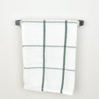 Plaid towel hanging on a pewter towel rack against a white background - front view