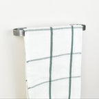 Plaid towel hanging on a pewter towel rack against a white background - left view