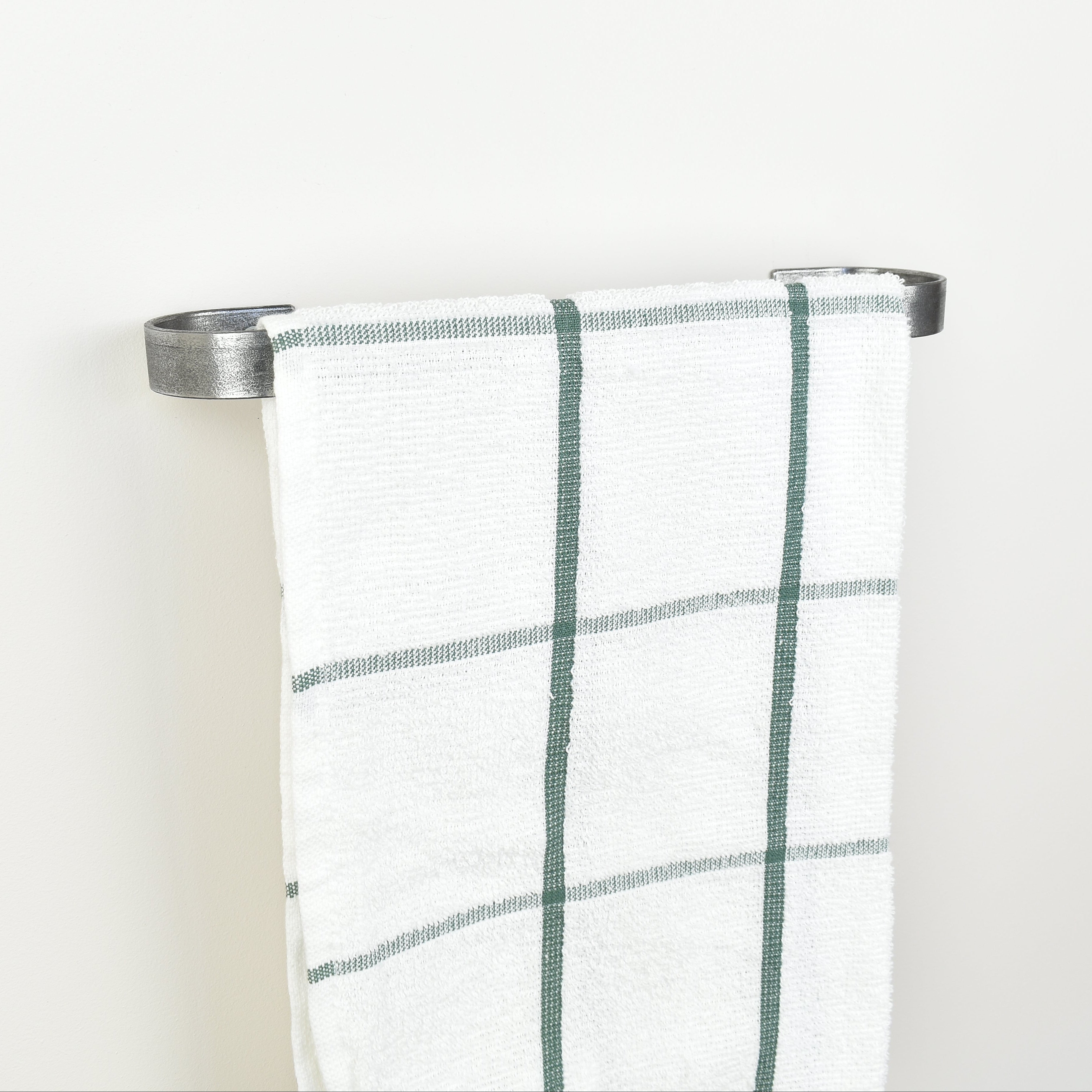 Plaid towel hanging on a pewter towel rack against a white background - left view