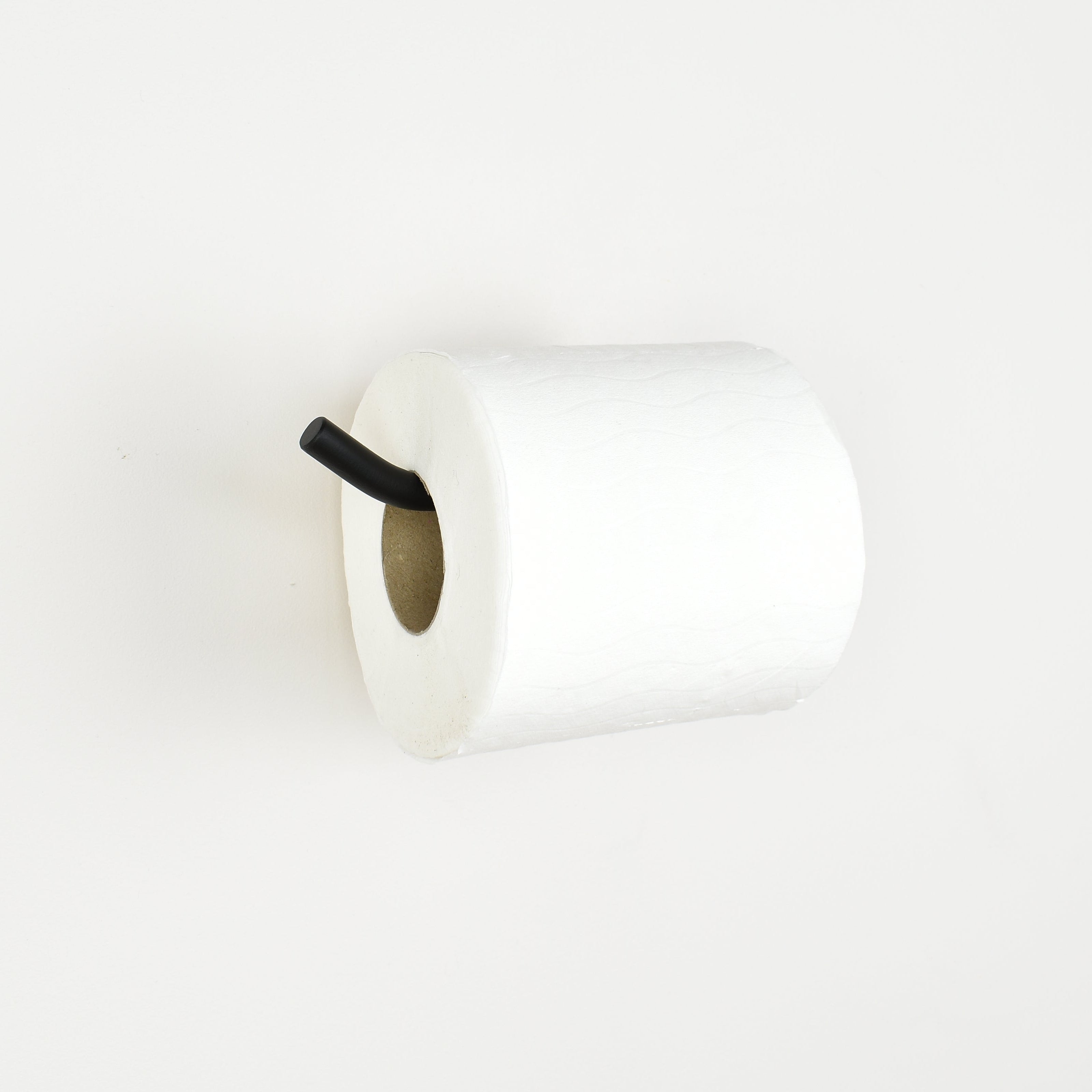 White toilet paper roll on a black metal toilet paper bar with white background