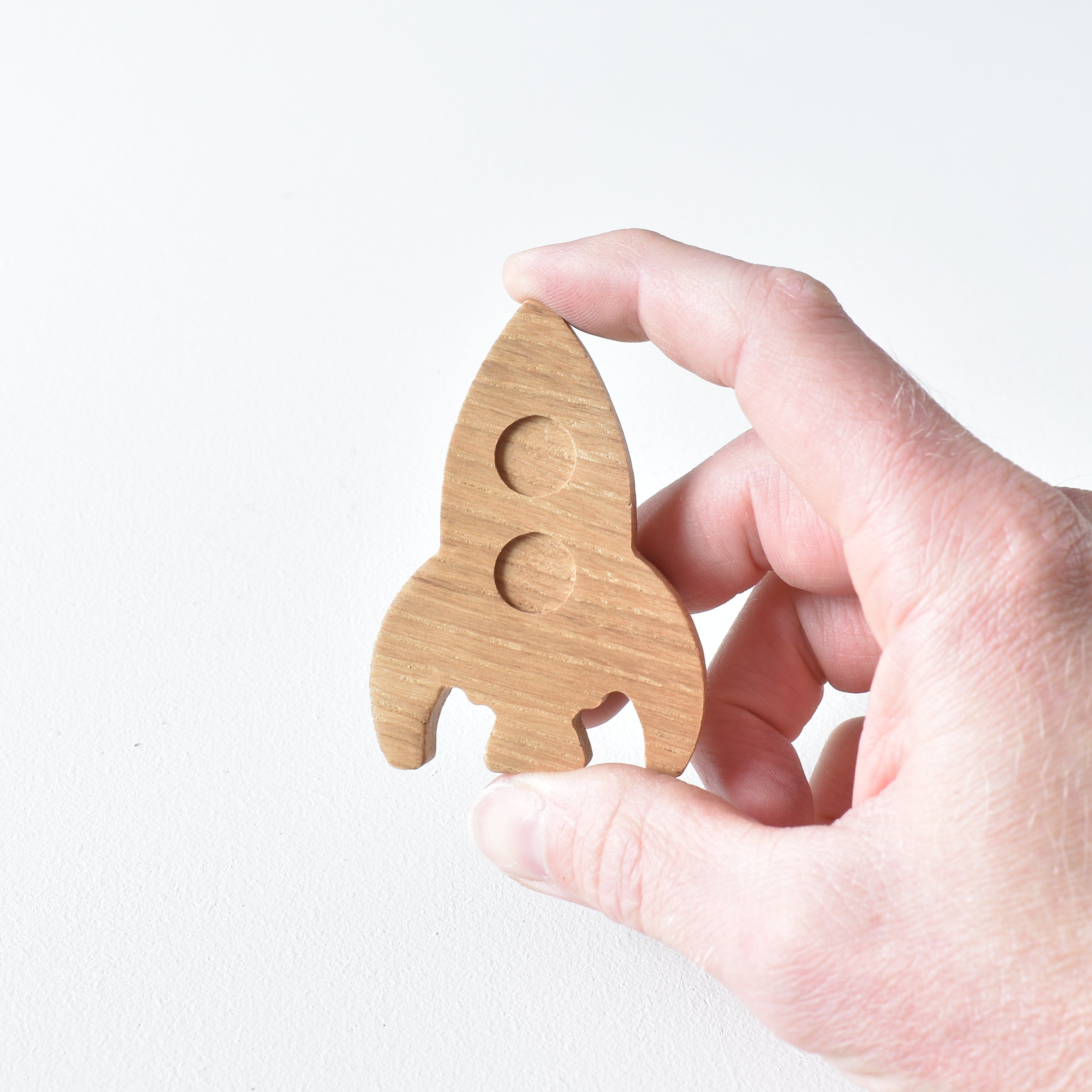 Hand holding handmade oak rocket drawer knob showing raised window detail and natural wood grain