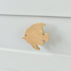 Oak fish drawer knob fitted to a white chest of drawers showing natural wood grain