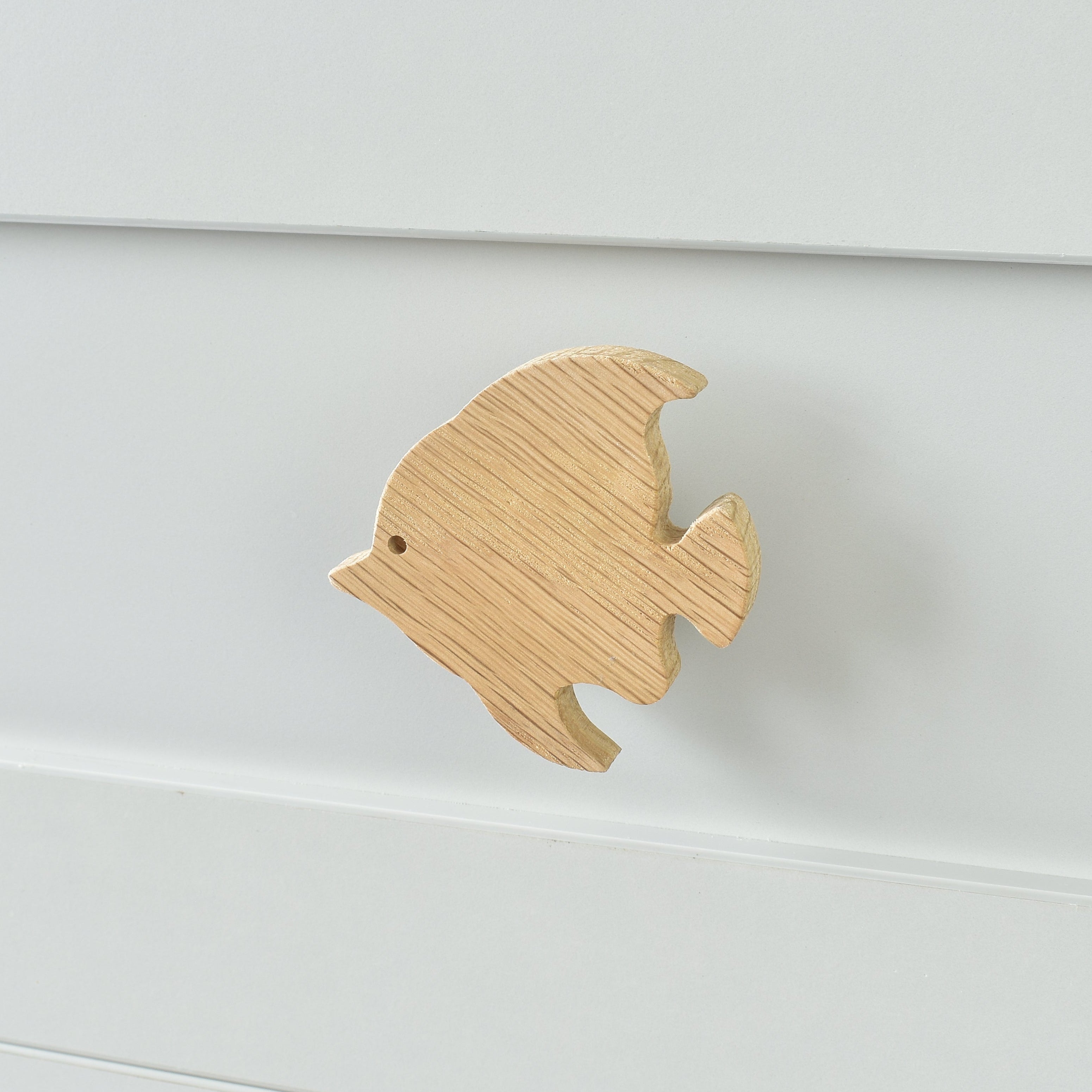 Oak fish drawer knob fitted to a white chest of drawers showing natural wood grain