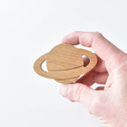 Hand holding handmade oak planet drawer knob showing ring detail and natural wood grain