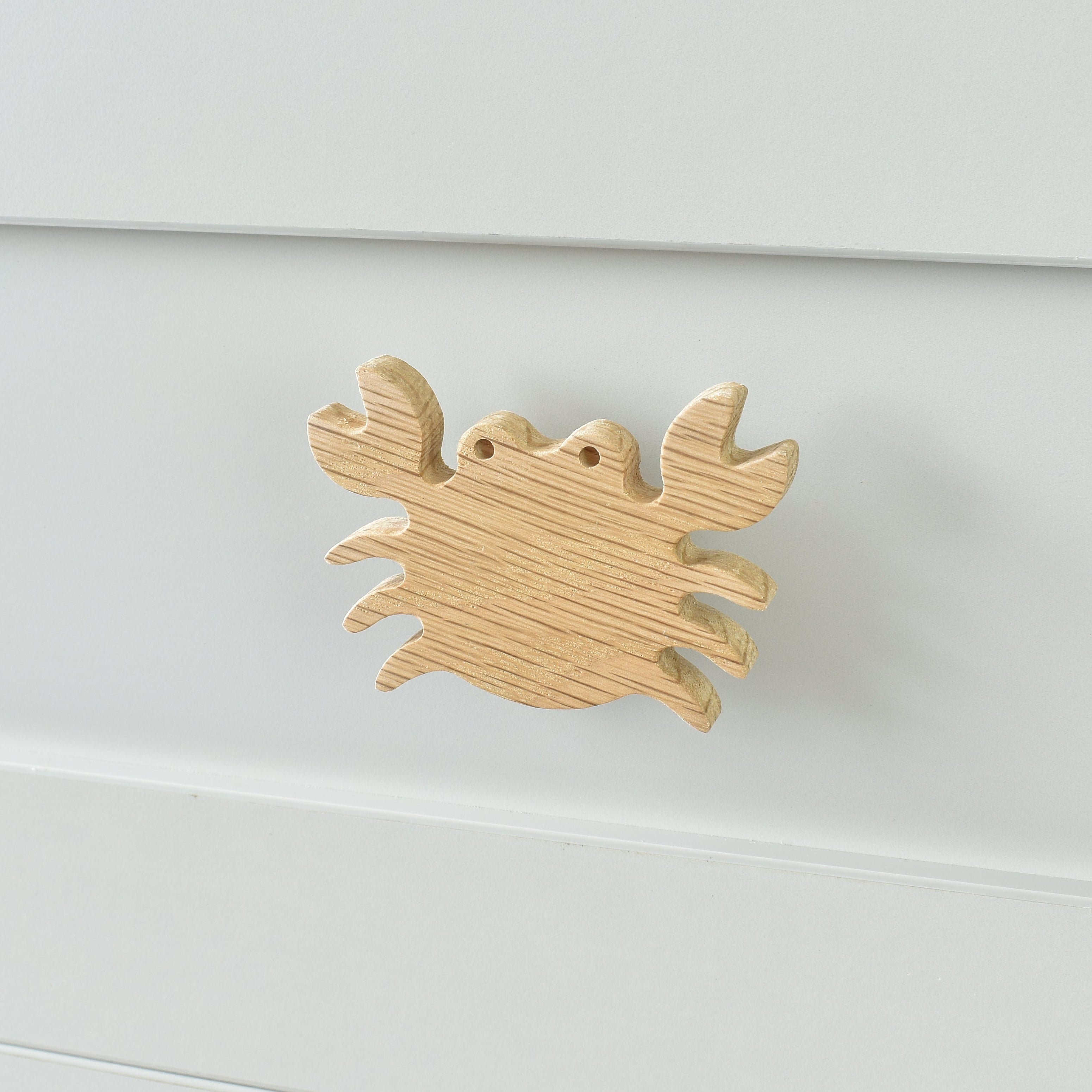 Oak crab drawer knob fitted to a white chest of drawers showing natural wood grain