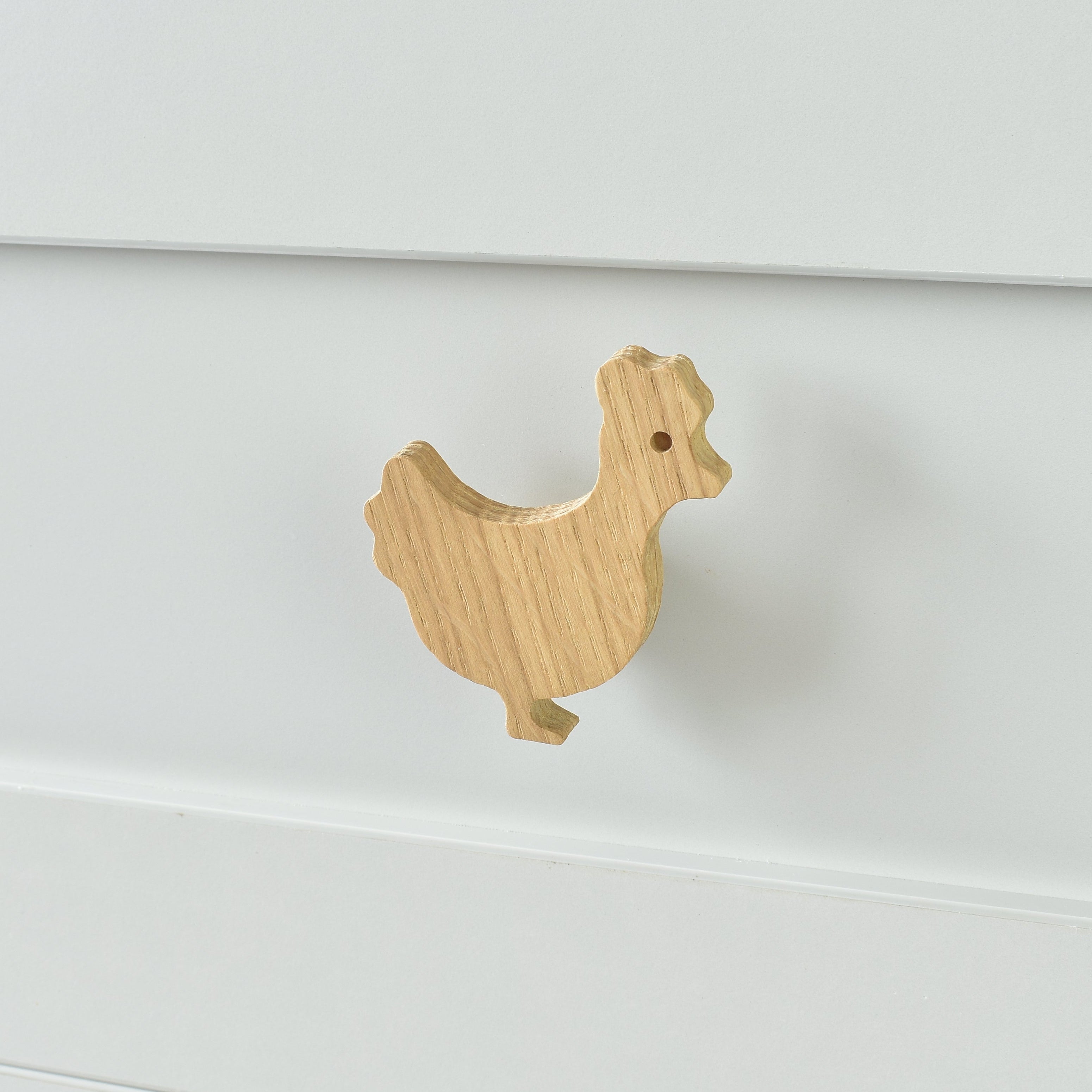 Oak chicken drawer knob fitted to a white chest of drawers showing natural wood grain