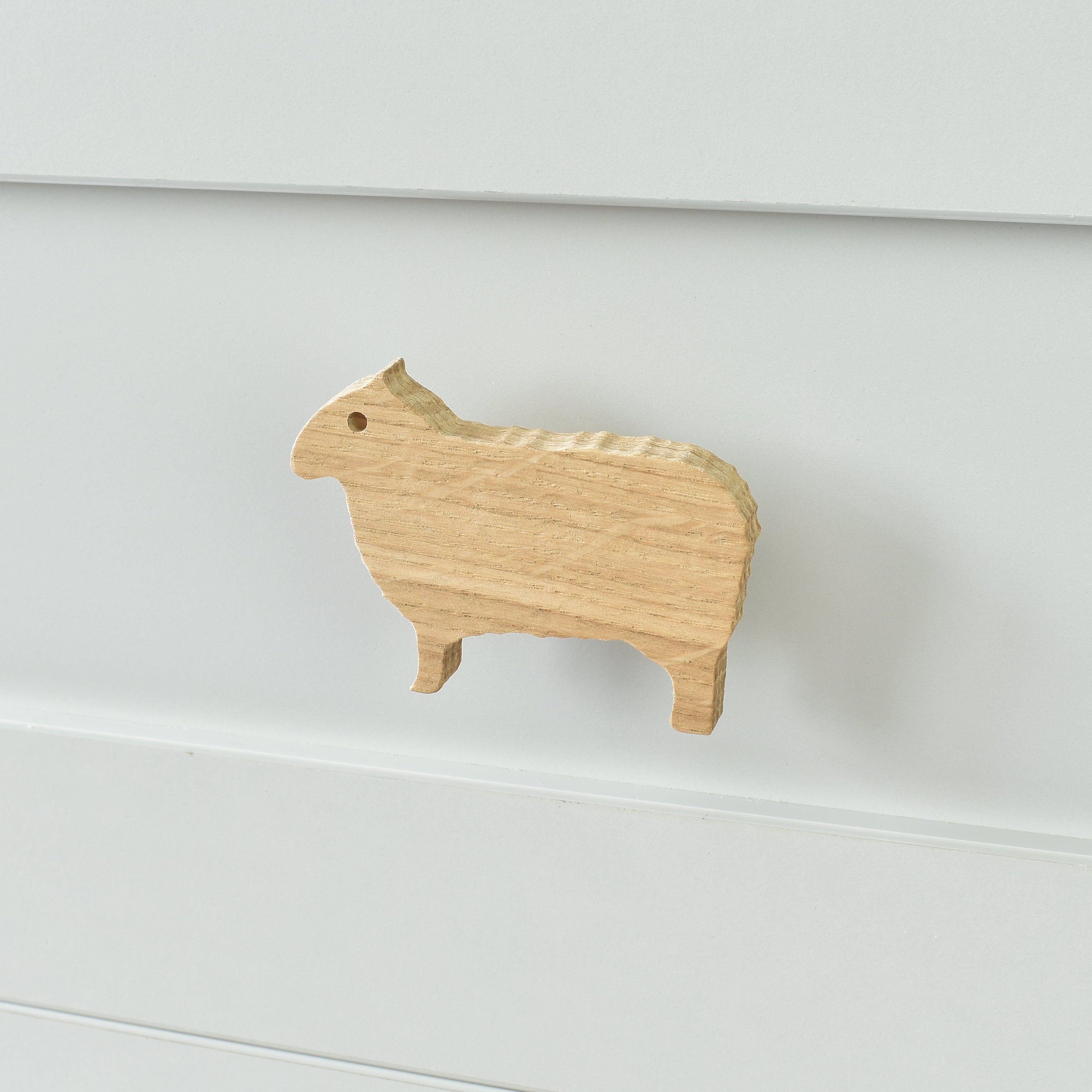 Oak sheep drawer knob fitted to a white chest of drawers showing natural wood grain