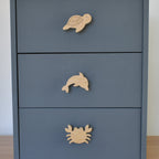 Oak ocean animal drawer knobs fitted to a blue chest of drawers showing turtle, dolphin and crab designs