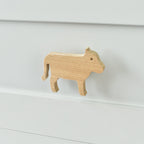 Oak cow drawer knob fitted to a white chest of drawers showing natural wood grain
