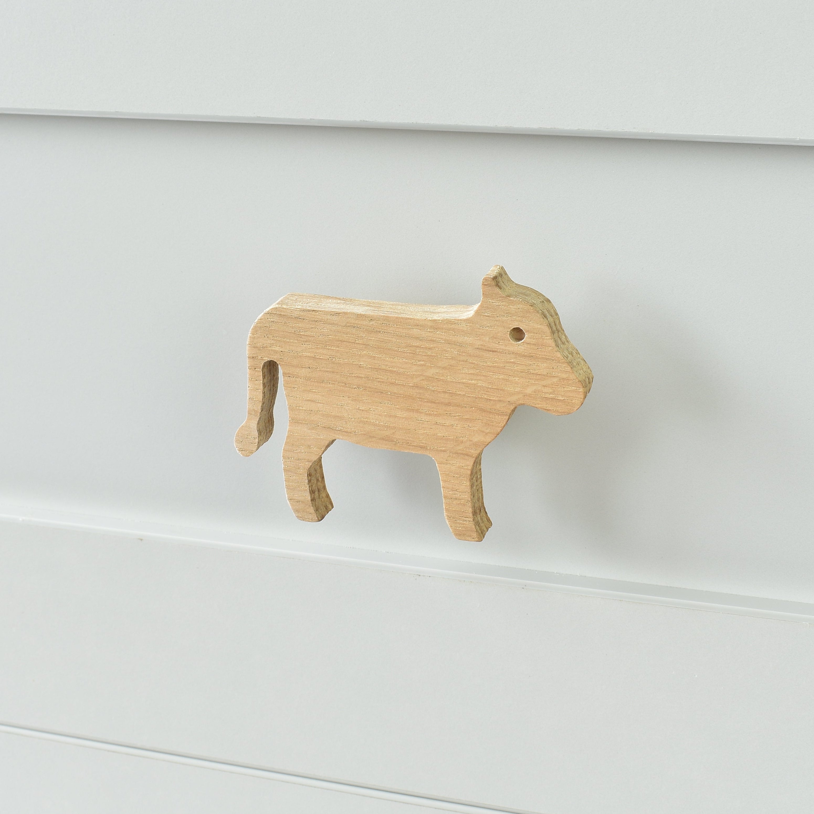 Oak cow drawer knob fitted to a white chest of drawers showing natural wood grain