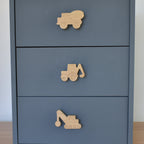 Oak construction vehicle drawer knobs fitted to a blue chest of drawers showing cement truck, digger and crane designs