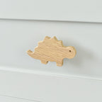 Oak stegosaurus drawer knob fitted to a white chest of drawers showing natural wood grain