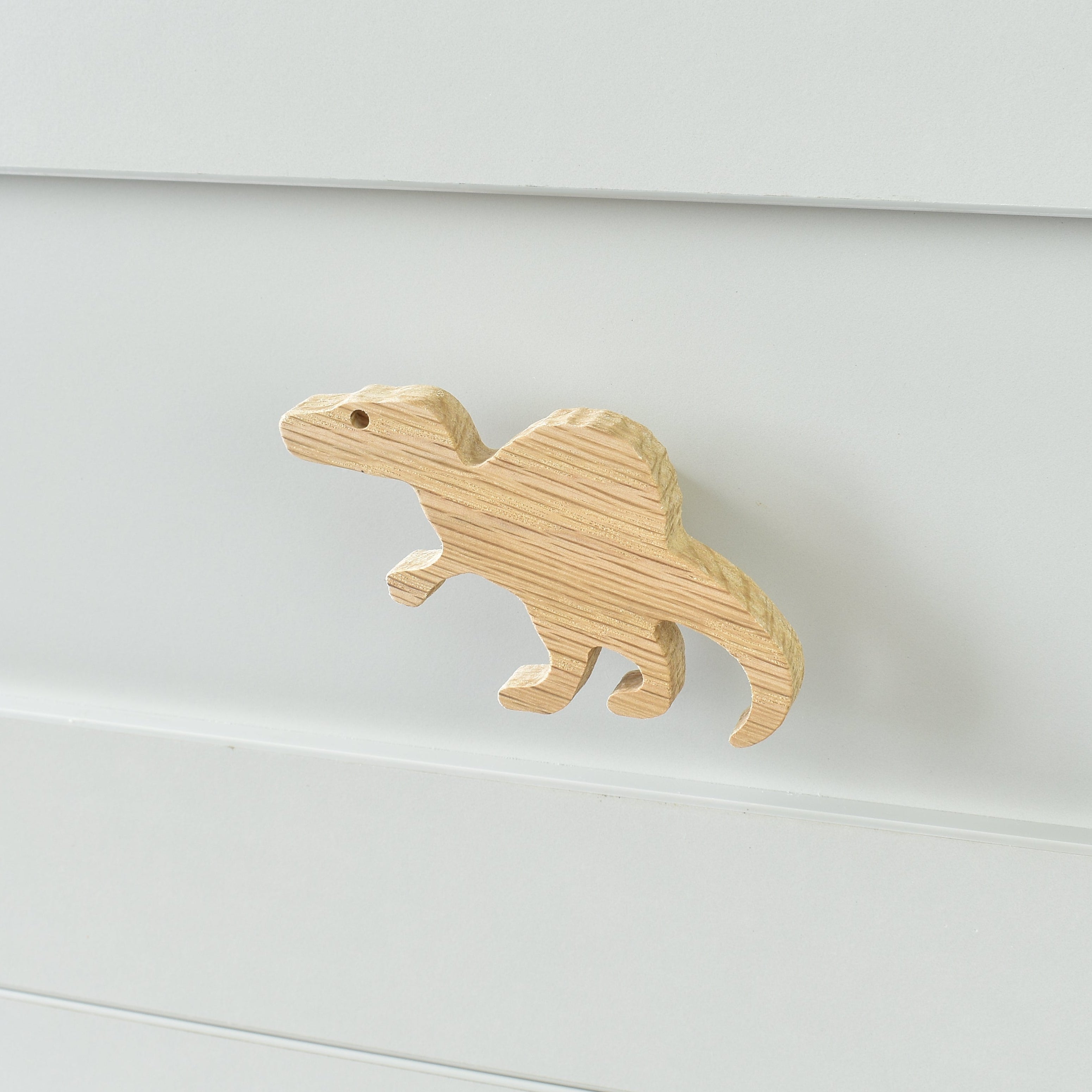 Oak spinosaurus drawer knob fitted to a white chest of drawers showing natural wood grain