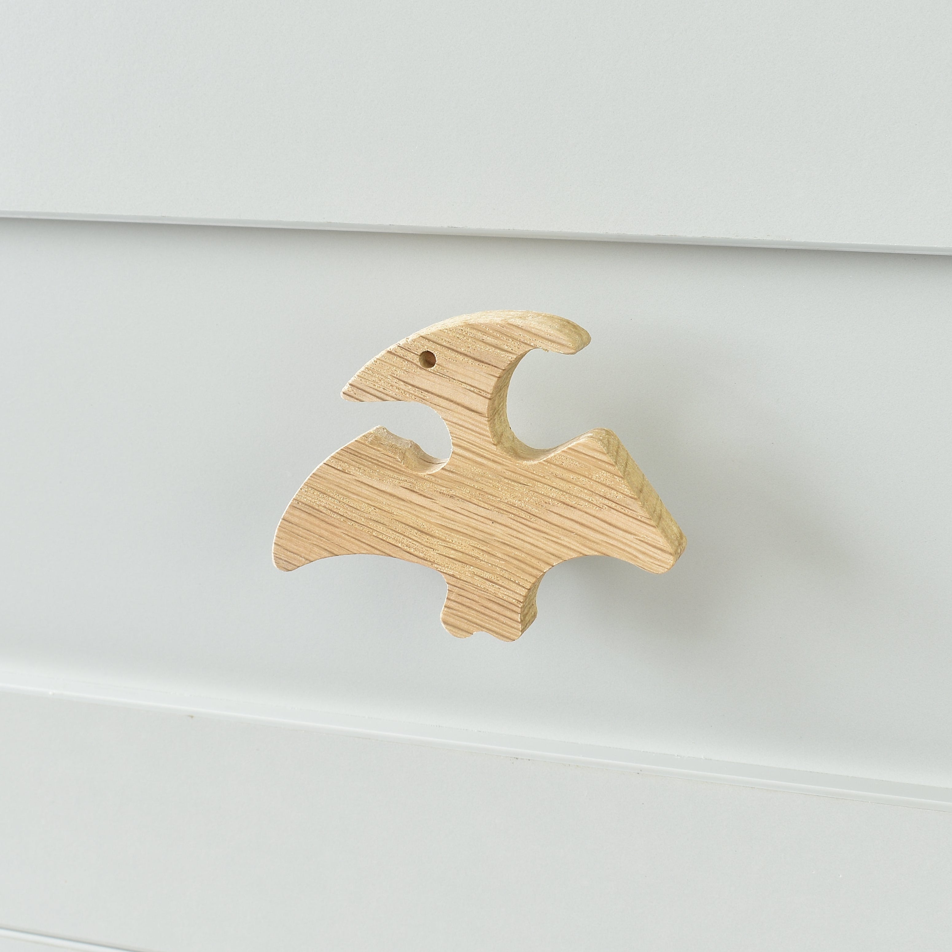 Oak pterodactyl drawer knob fitted to a white chest of drawers showing natural wood grain