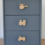 Oak transport vehicle drawer knobs fitted to a blue chest of drawers showing helicopter, train and motorbike designs