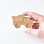Hand holding handmade oak dump truck drawer knob showing raised detail and natural wood grain
