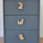 Oak woodland animal drawer knobs fitted to a blue chest of drawers showing rabbit, fox and owl designs