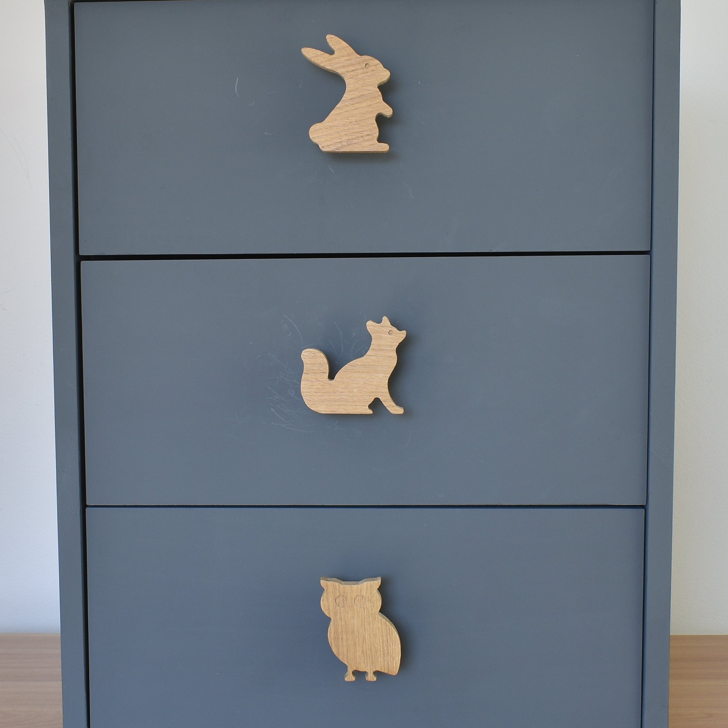 Oak woodland animal drawer knobs fitted to a blue chest of drawers showing rabbit, fox and owl designs