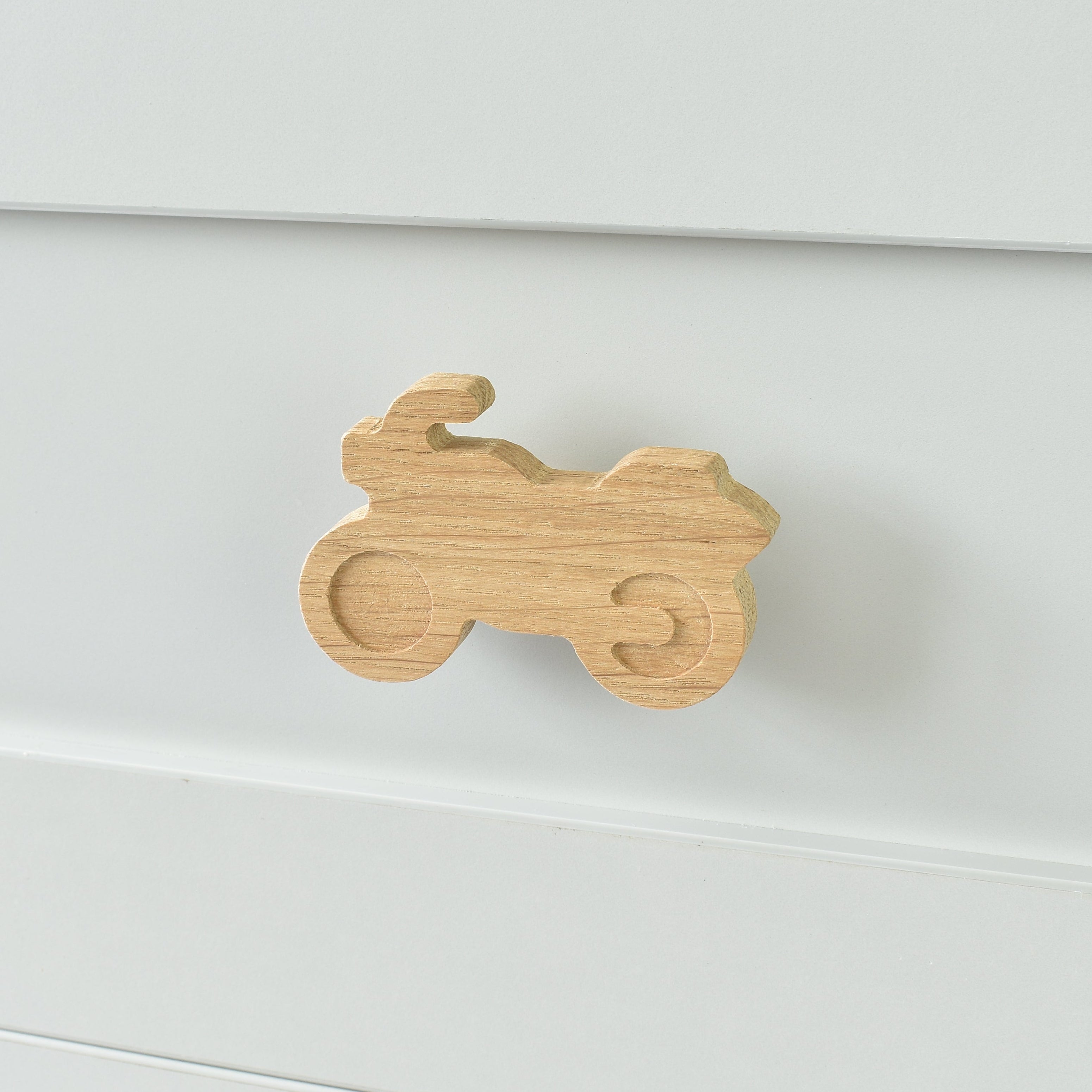 Oak motorbike drawer knob fitted to a white chest of drawers showing natural wood grain
