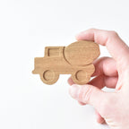 Hand holding handmade oak cement truck drawer knob showing raised detail and natural wood grain
