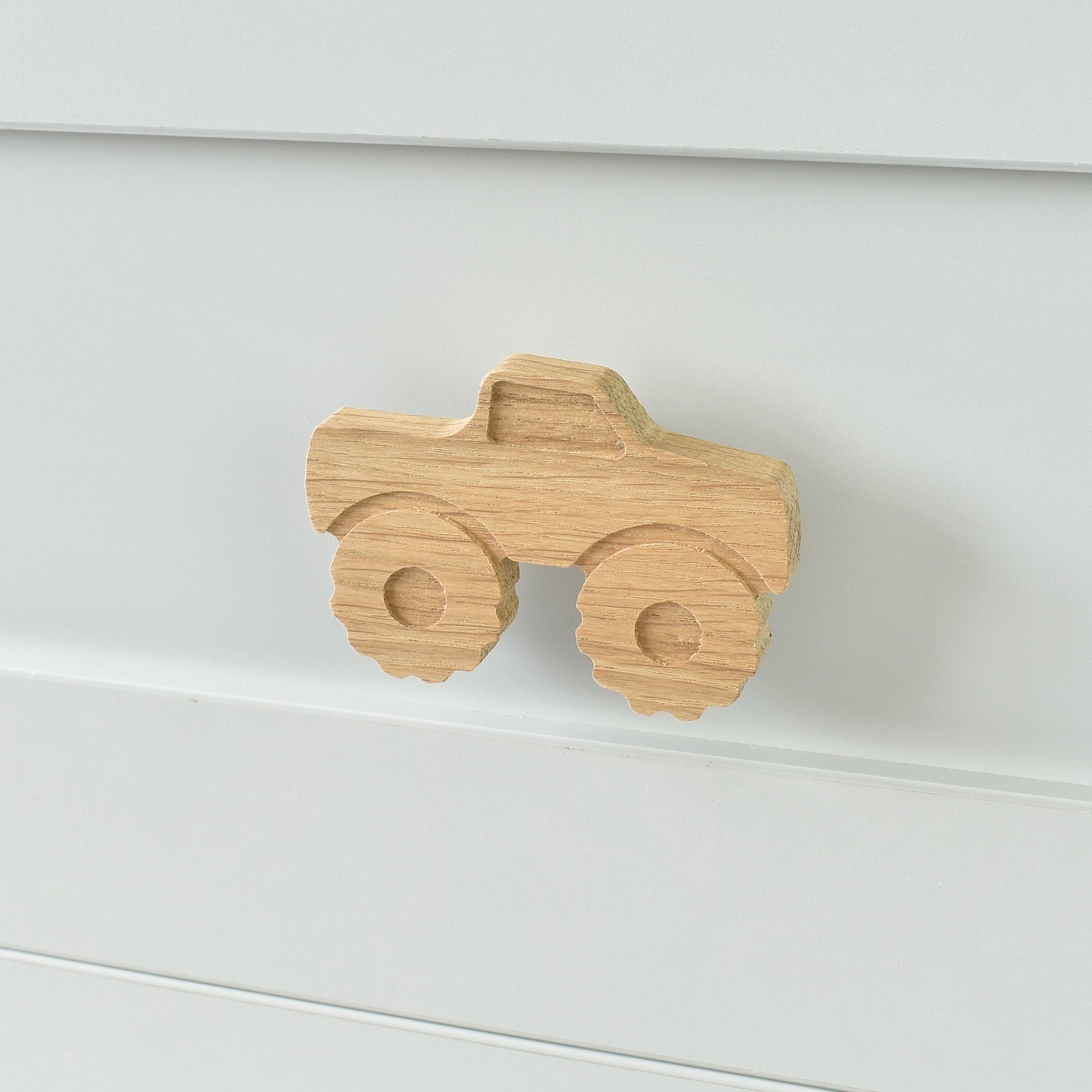 Oak monster truck drawer knob fitted to a white chest of drawers showing natural wood grain
