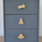 Oak space themed drawer knobs fitted to a blue chest of drawers showing shooting star, rocket and alien spaceship designs