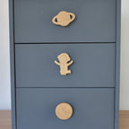 Oak space themed drawer knobs fitted to a blue chest of drawers showing planet, astronaut and moon designs