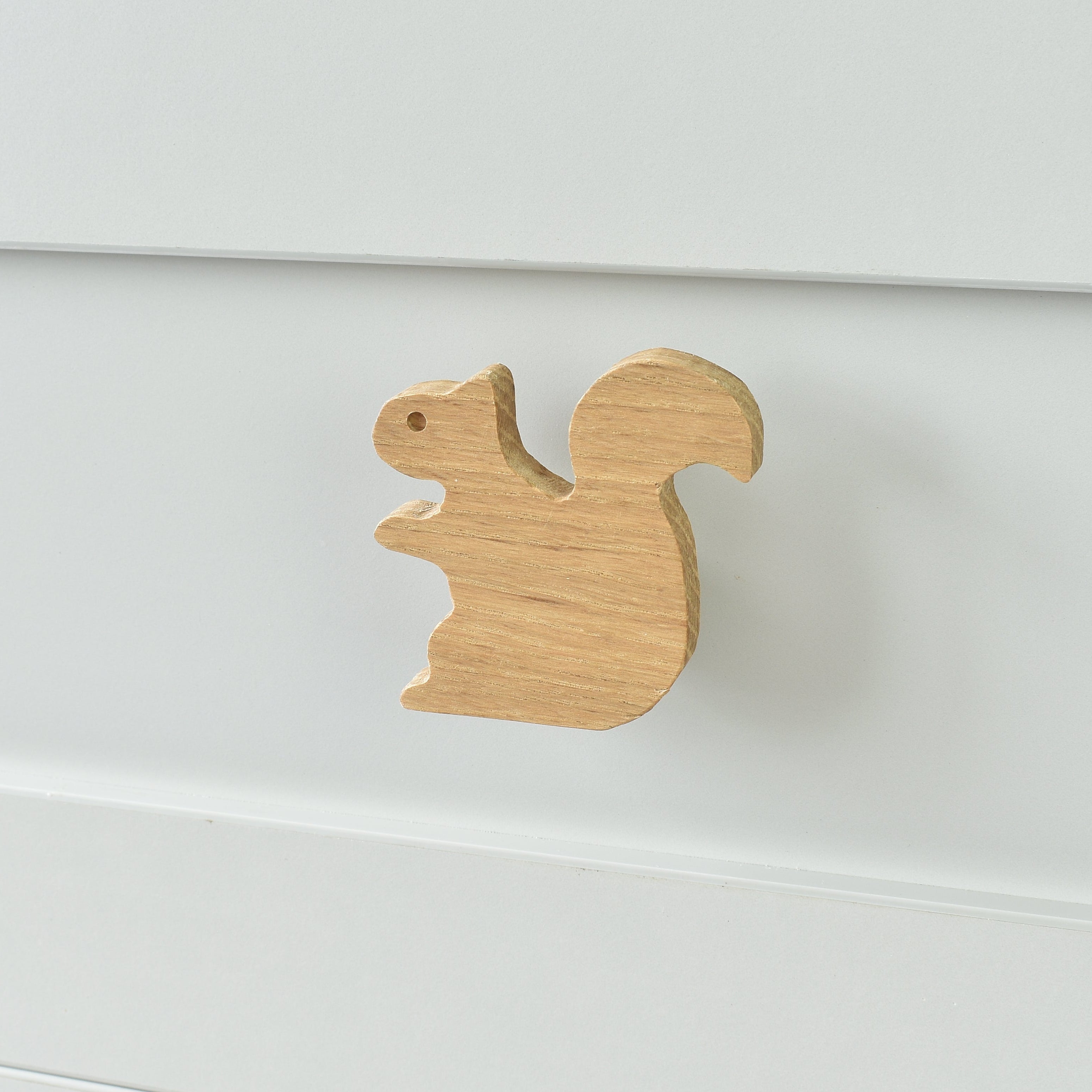 Oak squirrel drawer knob fitted to a white chest of drawers showing natural wood grain