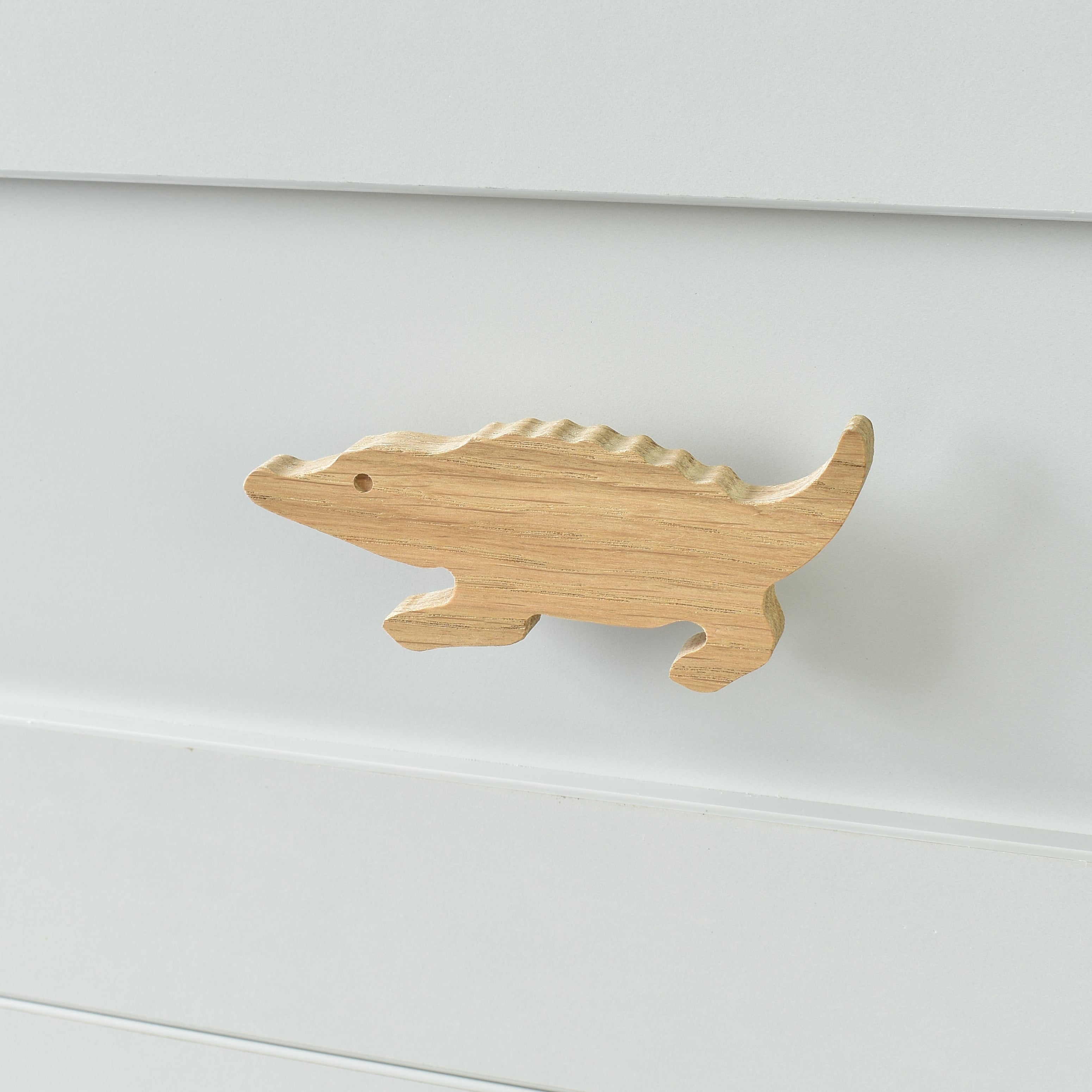 Oak crocodile drawer knob fitted to a white chest of drawers showing natural wood grain