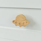 Oak alien spaceship drawer knob fitted to a white chest of drawers showing natural wood grain
