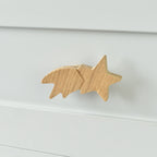 Oak shooting star drawer knob fitted to a white chest of drawers showing natural wood grain