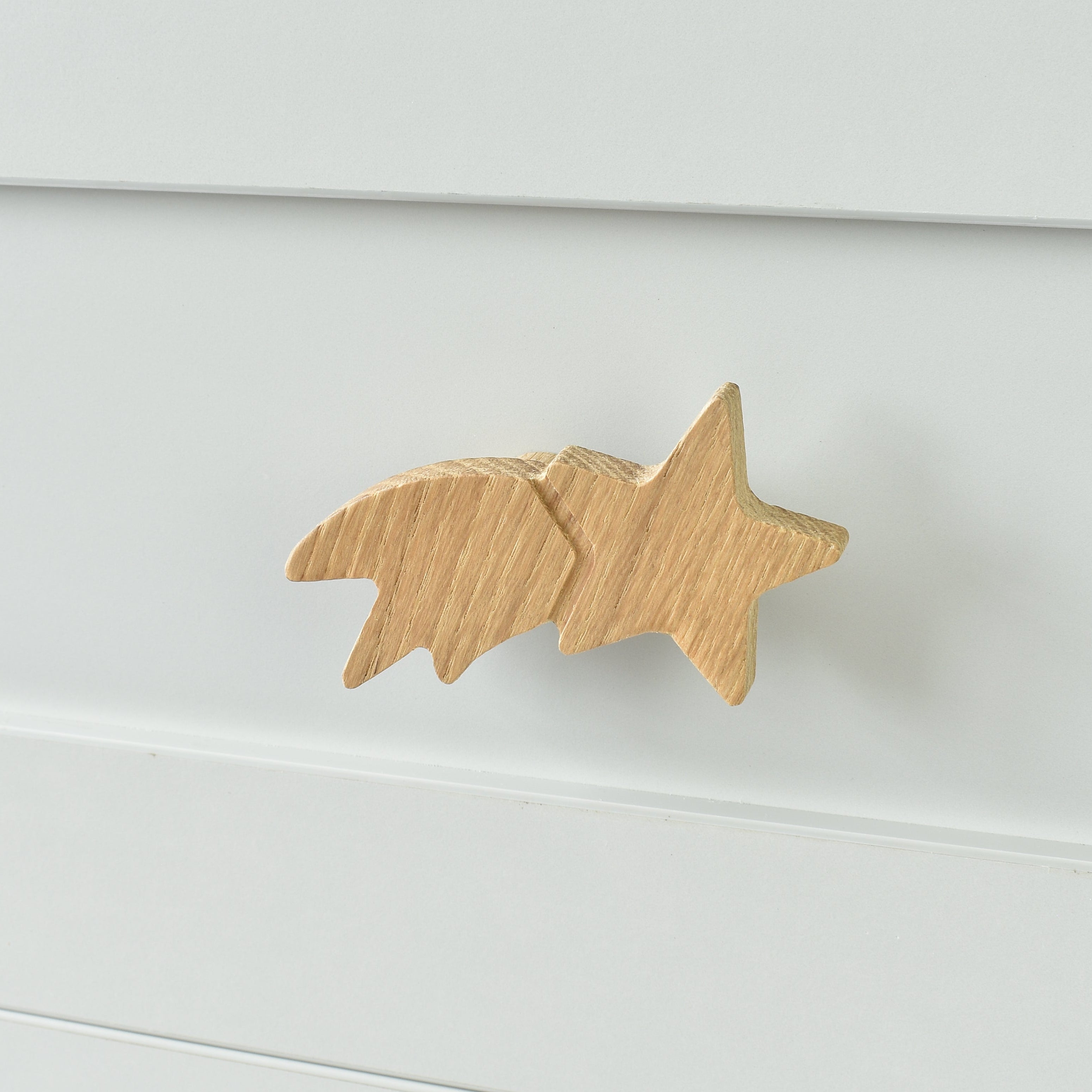 Oak shooting star drawer knob fitted to a white chest of drawers showing natural wood grain