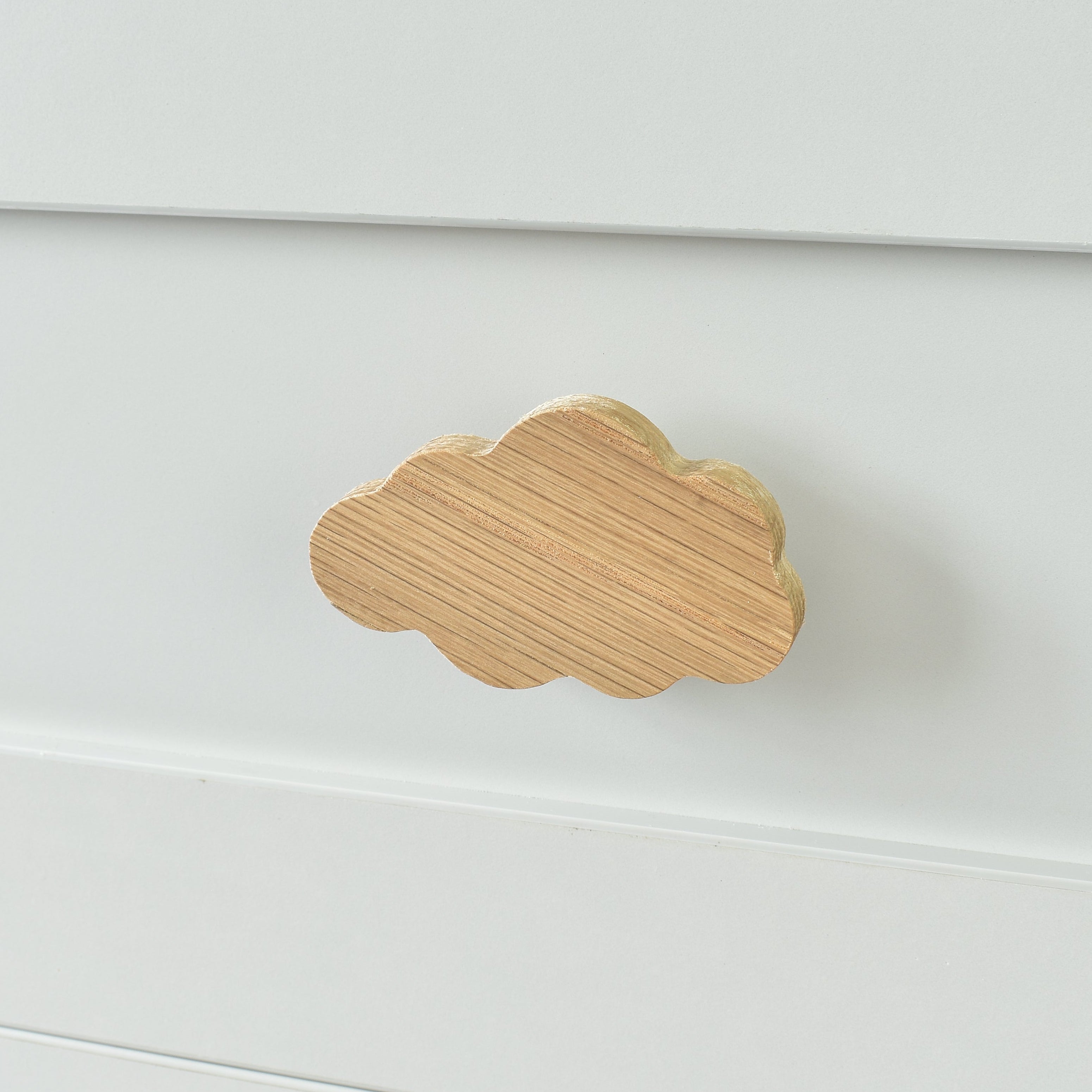 Oak cloud drawer knob fitted to a white chest of drawers showing natural wood grain